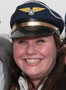 A woman smiling and wearing a blue hat with a gold winged emblem and a star in the center, reminiscent of the elegance found in luxury kitchen appliance design.