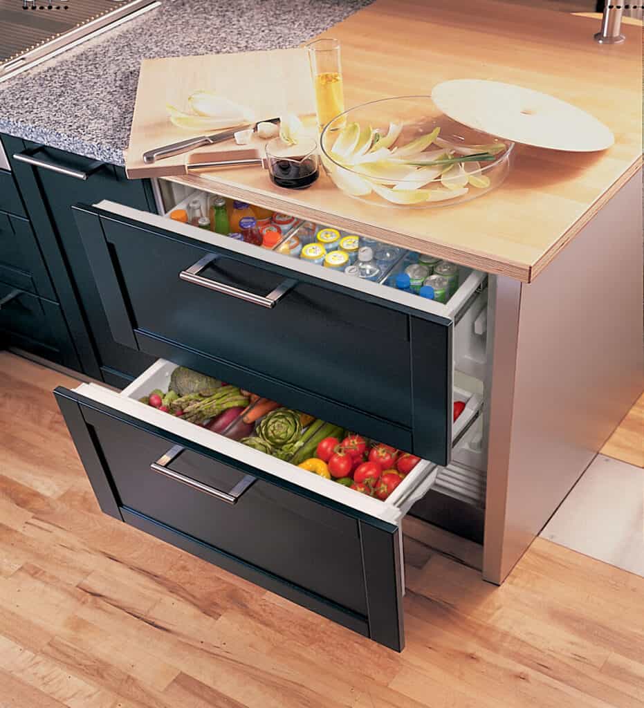 Two open refrigerator drawers built into a kitchen island showcase drinks on top and fresh vegetables and fruits below—a perfect addition for any luxury kitchen appliance display or modern kitchen showroom.