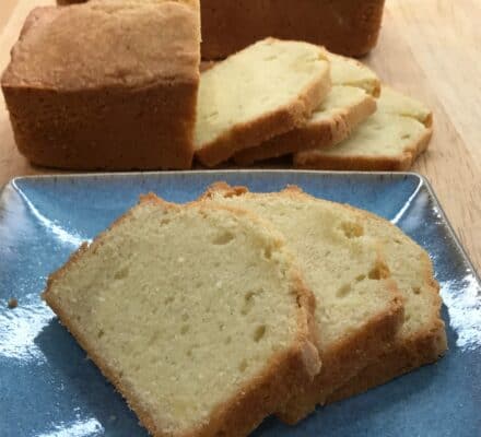 Sliced pound cake displayed on a blue plate, with a loaf and additional slices in the background on a wooden surface—perfect for showcasing in a luxury kitchen appliance showroom.