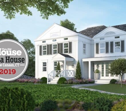 A two-story white house with columns and shutters, surrounded by greenery and flowers, featuring a "This Old House Idea House 2019 New Canaan, CT" badge on the left—perfect inspiration for your next kitchen showroom or sub zero appliance upgrade.