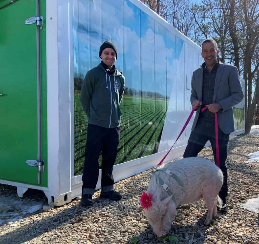 Freight Farm Operator Nathan Liberty with Clarke President Sean Clarke and Winnie the Pig celebrate Clarke’s Freight Farm expansion.