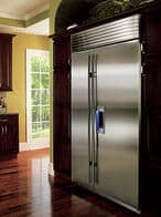 Stainless steel refrigerator built into dark wood cabinetry, with a window showing a green outdoor scene in the background—an elegant luxury kitchen appliance fit for any modern home.