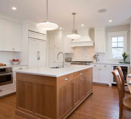 Kitchen with white cabinets, wood floors, and matching wood sided counter island.