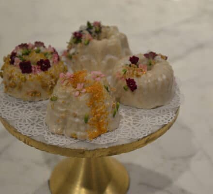Elegant Persian Love Cake adorned with rose petals, pistachios, and a dusting of powdered sugar