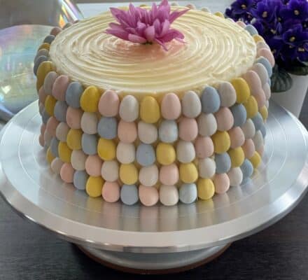 Festive Easter egg carrot tea cake topped with colorful icing and decorated with mini chocolate eggs