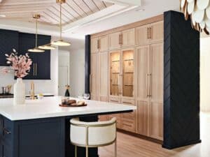 Julie Lyons is a kitchen designer with a beautiful design aesthetic, integrating Sub-Zero refrigerators and freezers in a seamless way in this wall of rift white oak with glass, brass and deep blue accents.