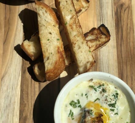 Perfectly baked dipping eggs with runny yolks, served in individual ramekins and garnished with fresh herbs