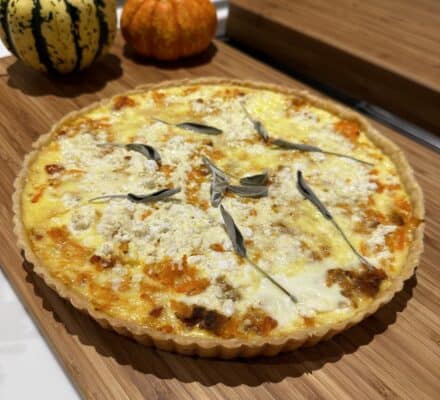 Golden Butternut Squash and Bacon Tart with a flaky crust, garnished with fresh herbs, perfect for a savory and seasonal dish.