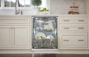An open dishwasher built into a modern white kitchen filled with clean dishes, with countertops displaying fruit and baked goods, perfectly complements the sub zero appliance for a true luxury kitchen appliance experience.