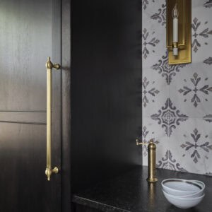 A black counter with a gold handle and a bowl on it, perfectly complementing a Wolf appliance in a modern kitchen showroom.