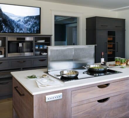 A clean stainless trim surrounds the induction cooktop with a downdraft ventilation system that retracts into the countertop when not in use.