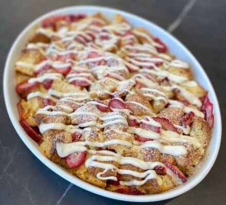 Delicious Strawberries and Cream Croissant Bake topped with fresh strawberries and a dusting of powdered sugar, perfect for a sweet breakfast or brunch treat.