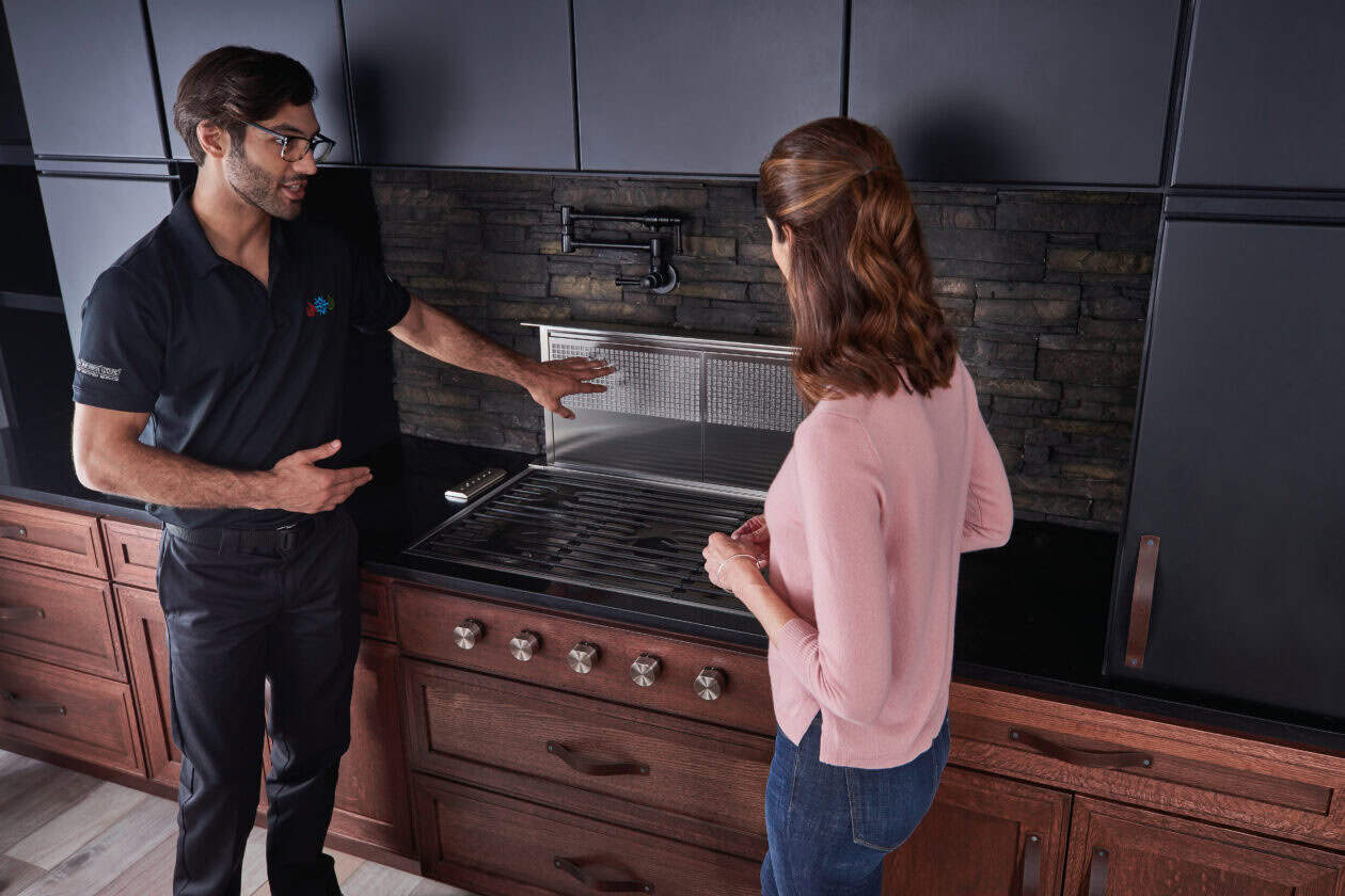A man and woman standing in front of a Wolf cooktop