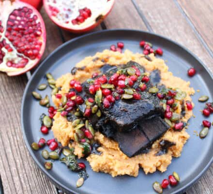 A plate of food with fruit alongside Black Cocoa & Espresso Braised Short Ribs.