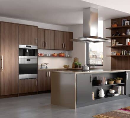 Modern kitchen with wood cabinets, stainless steel oven, open shelving, and a central island featuring a Wolf cooktop and grey cabinetry. Various kitchenware and utensils are visible.